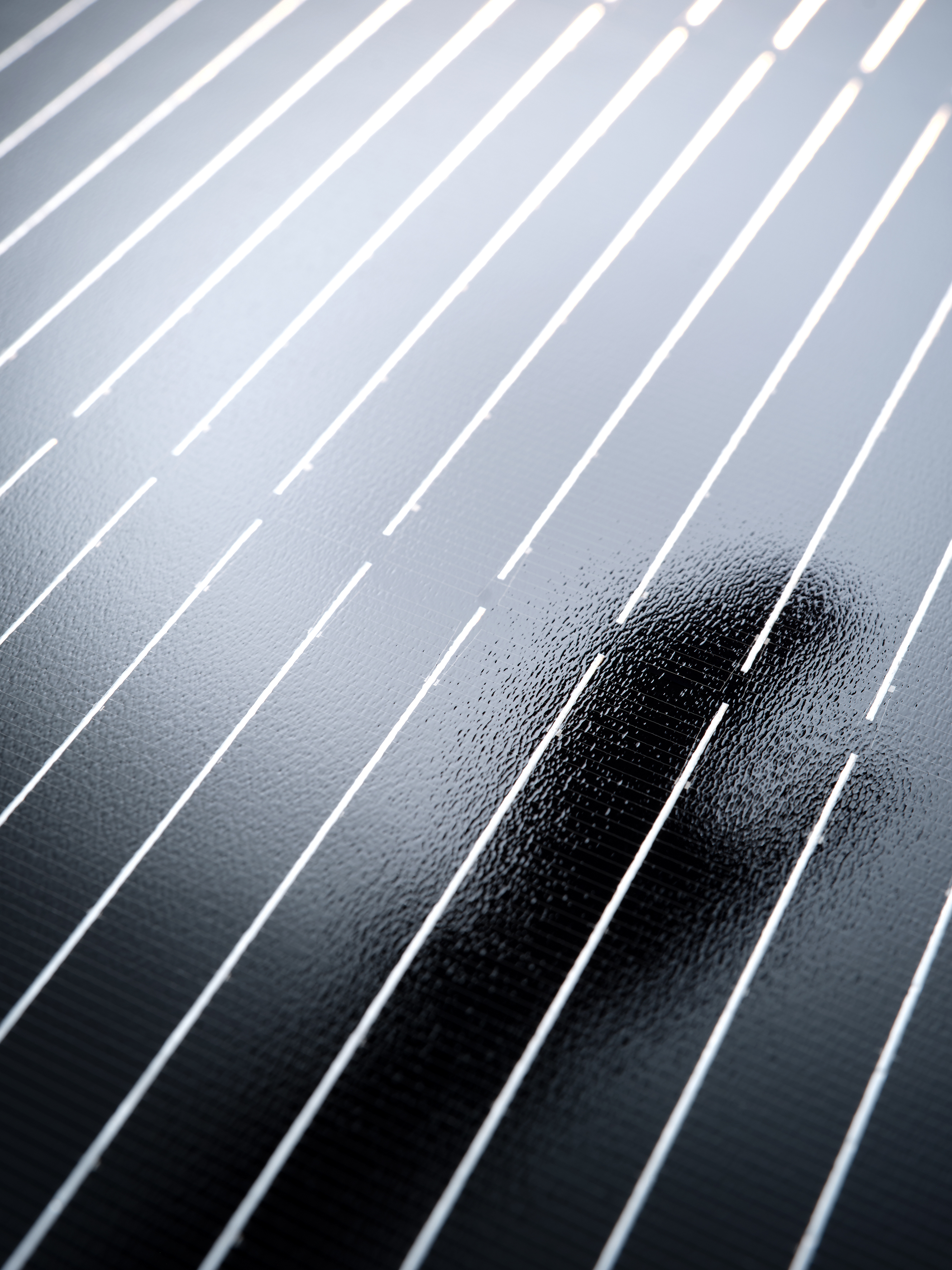 Close-up of photovoltaic surface with linear cell pattern and reflections
