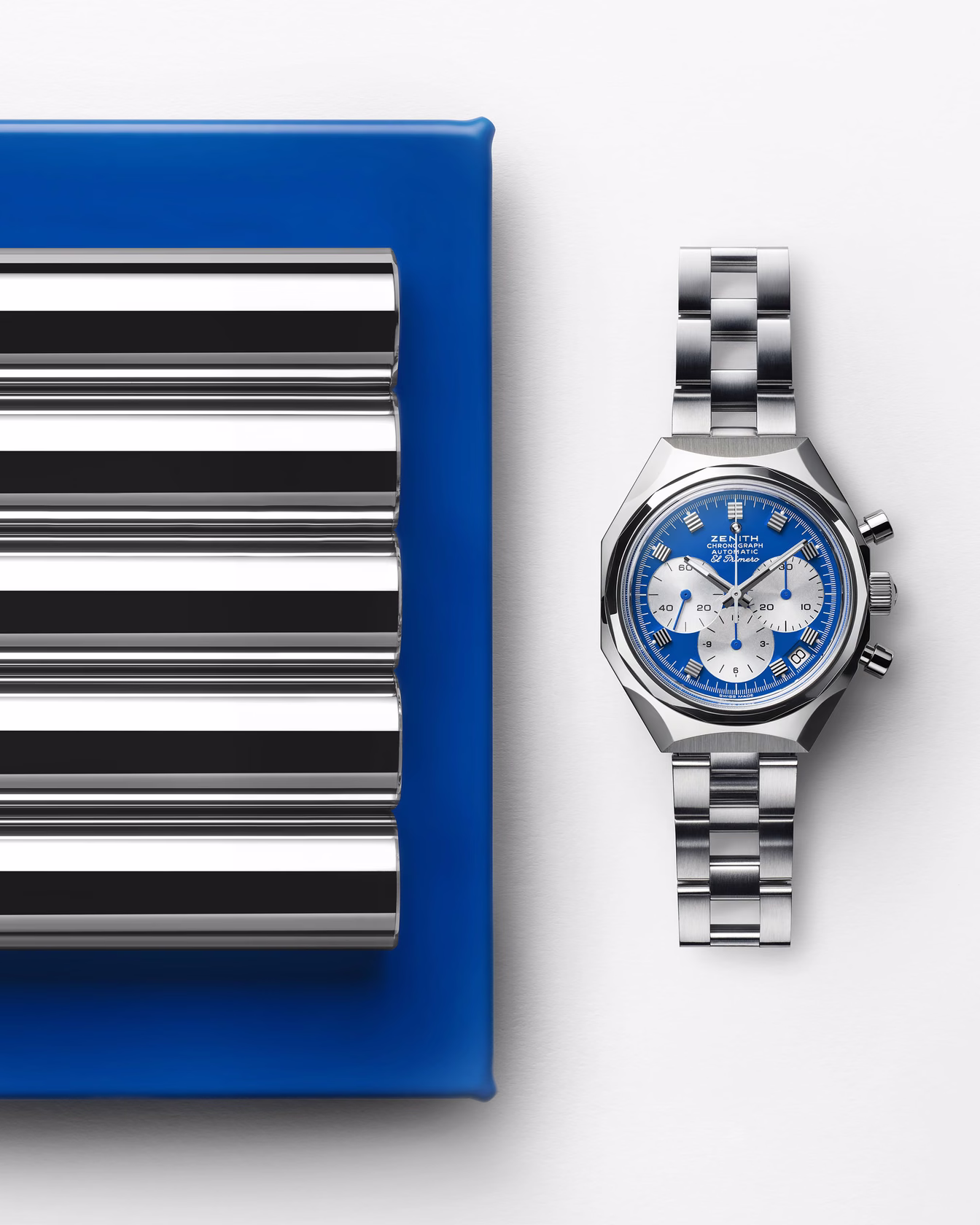 Watch positioned on blue panel with reflective metal structure and striped element