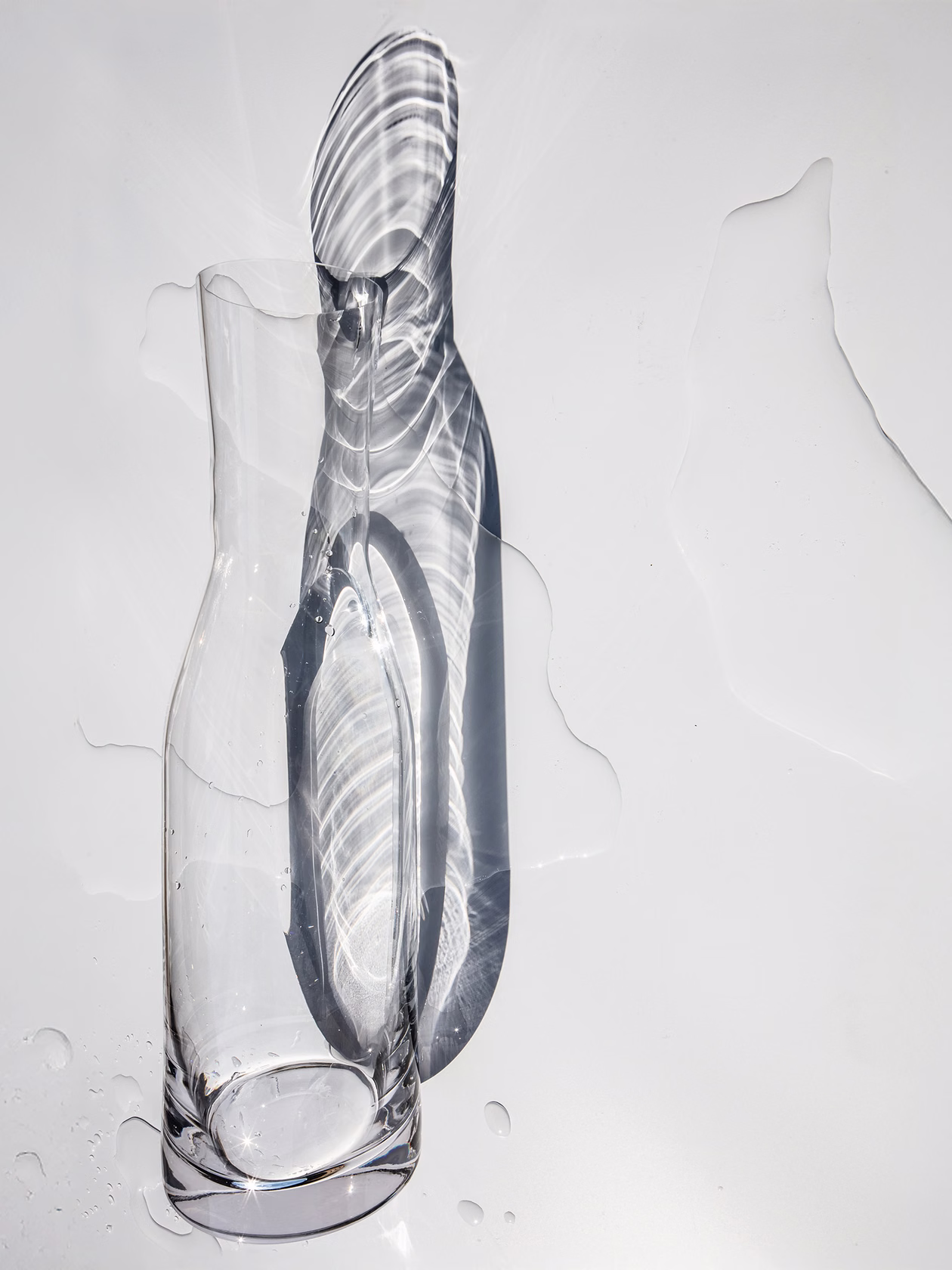 Glass water carafe with light reflections and water shadows