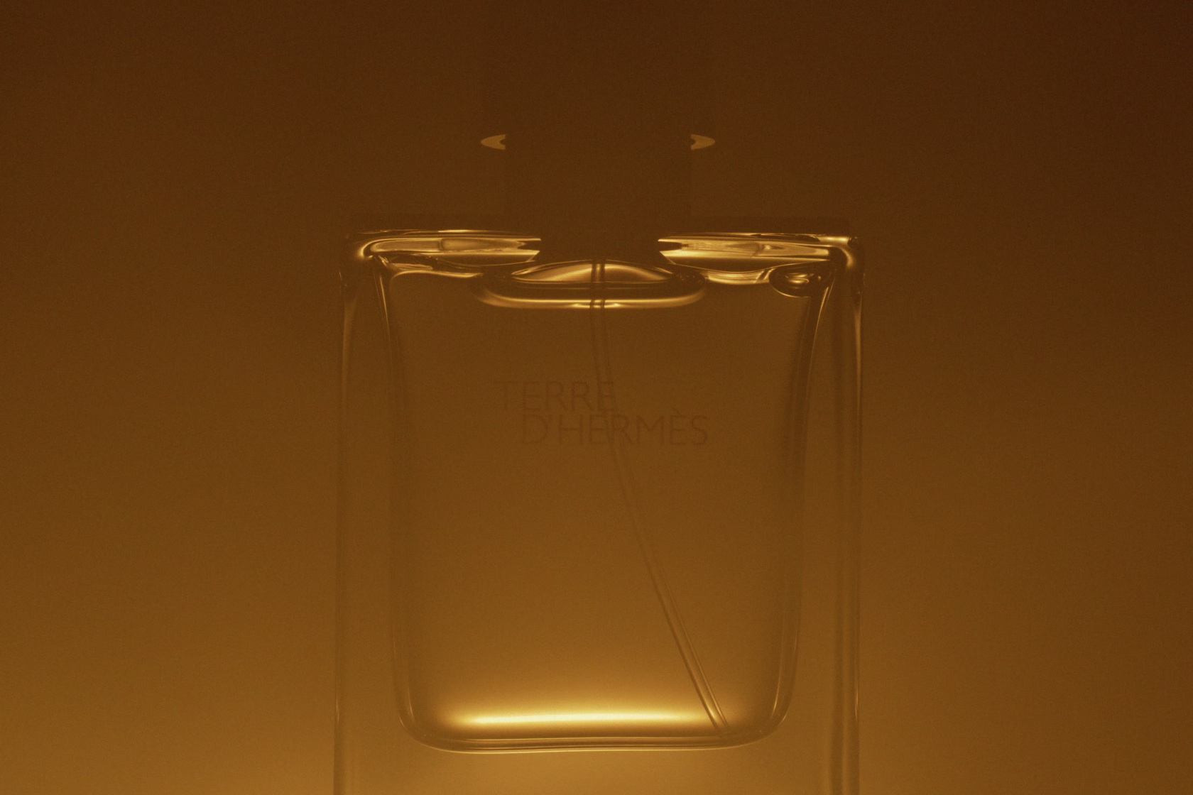 glass bottle partially immersed in orange haze with soft reflections
